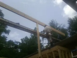 Carpenter setting a ridge beam over a new addition frame — Ice Dam Removal by Roofing Brothers in Bessie