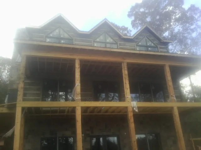 Dormers and porch framing on a large log home under construction — Roof Coating work by our crew in Bessie