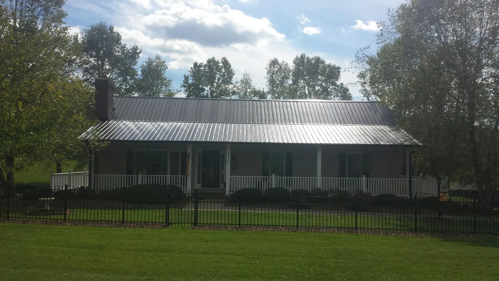Gray metal roof on a brick ranch with a full width front porch — Gutter Guard Installation work by our crew in Bessie