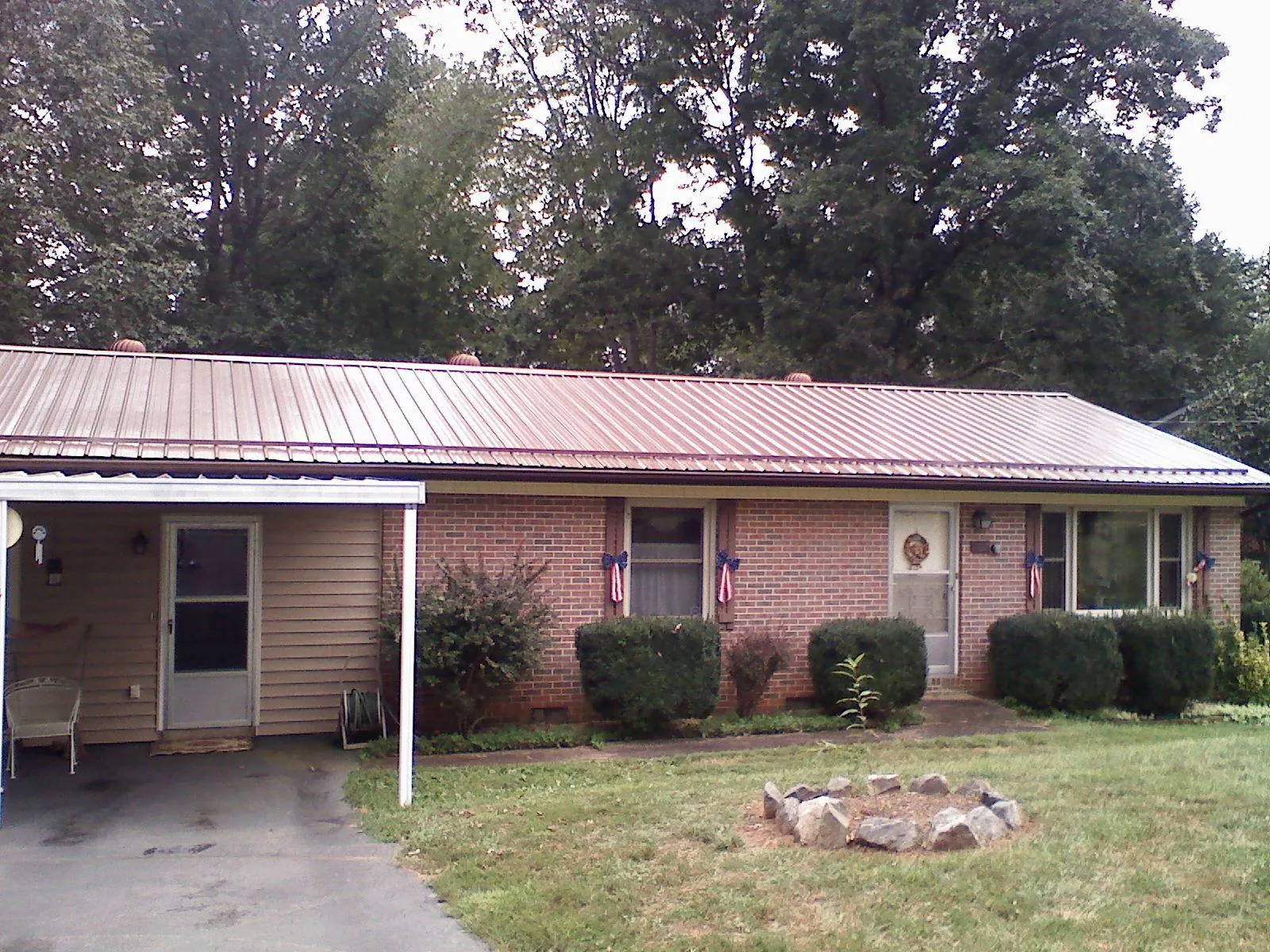 Bronze metal roof and carport on a brick ranch home — Roof Repair work by our crew in Bessie